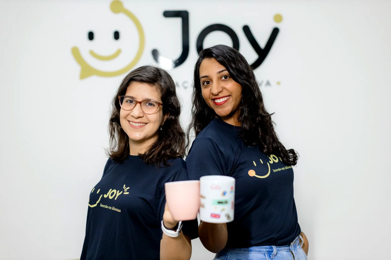 Thaís Fialho e Viviane Araújo, coordenadoras pedagógicas da Joy, recebendo visitantes com um sorriso